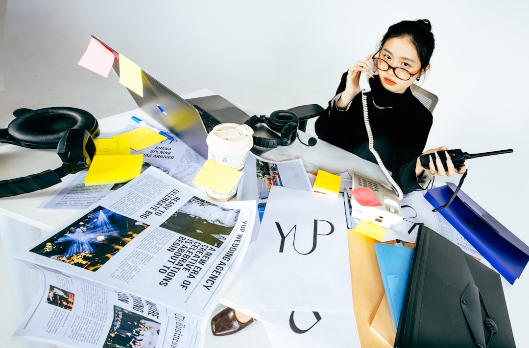 Woman on phone at messy desk with papers and laptop
