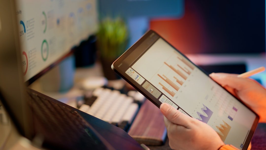 Someone analyzes financial data on a tablet — illustrating How to Increase AI Visibility: A 30-Day Practical Plan